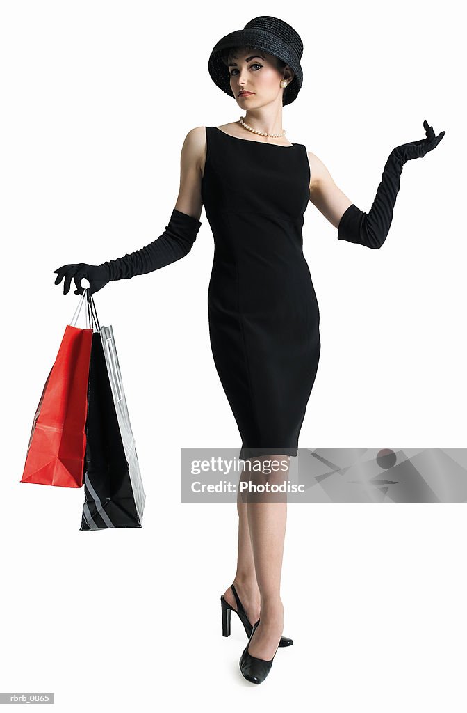 Silhouette of attractive sophisticated caucasian woman in black dress hat as she holds shopping bags