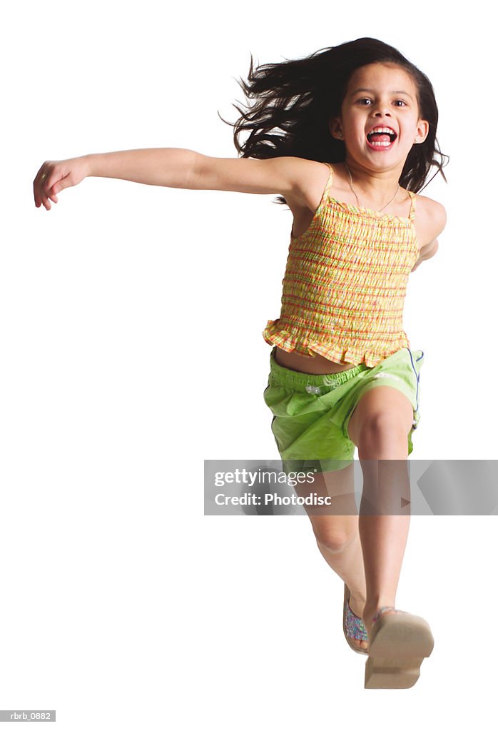 Silhouette of a caucasian female child in green shorts and a yellow shirt as she runs and jumps