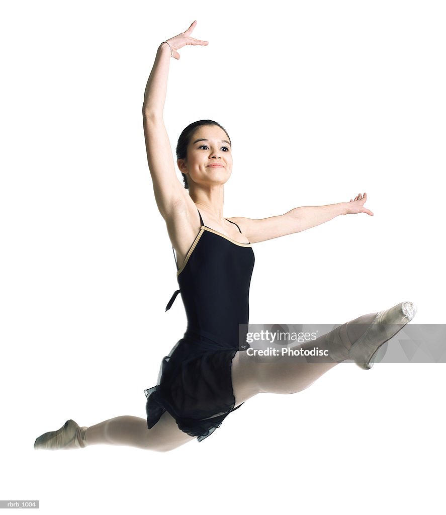 A female asian teenager in a black ballet outfit jumps and flies through the air