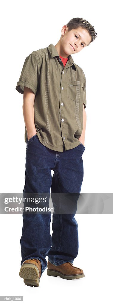 A caucasian male teen in jeans and a green shirt puts his hnads in his pockets and smirks