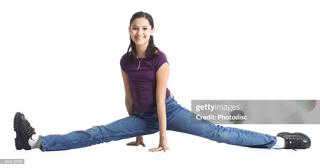 An ethnic teenage girl in jeans and a purple shirt does the splits