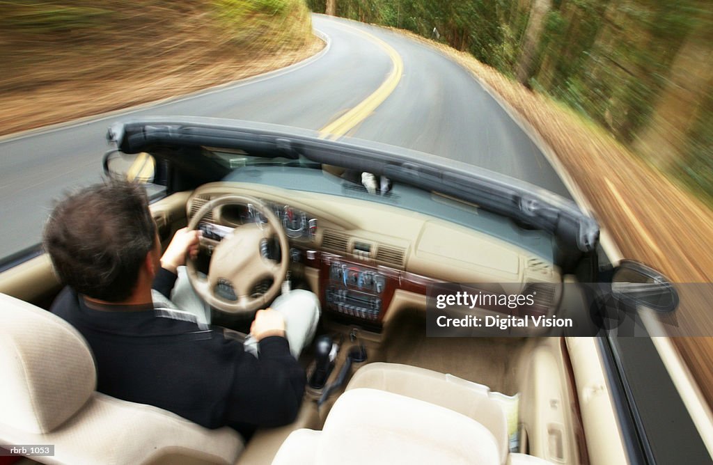 Lifestyle photograph of a man speeding down a highway in a convertible