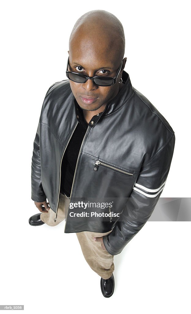 An adult african american man in a leather jacket and sunglasses smirks up at the camera