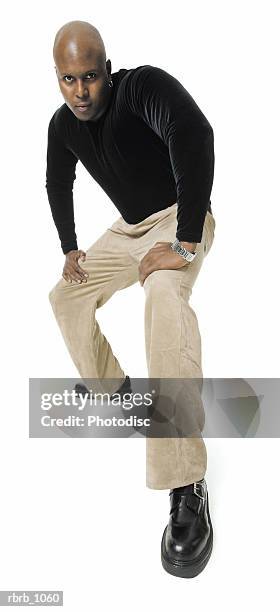an adult african american man in tan pants and a black shirt crouches down and glares into the camera - pants down bildbanksfoton och bilder