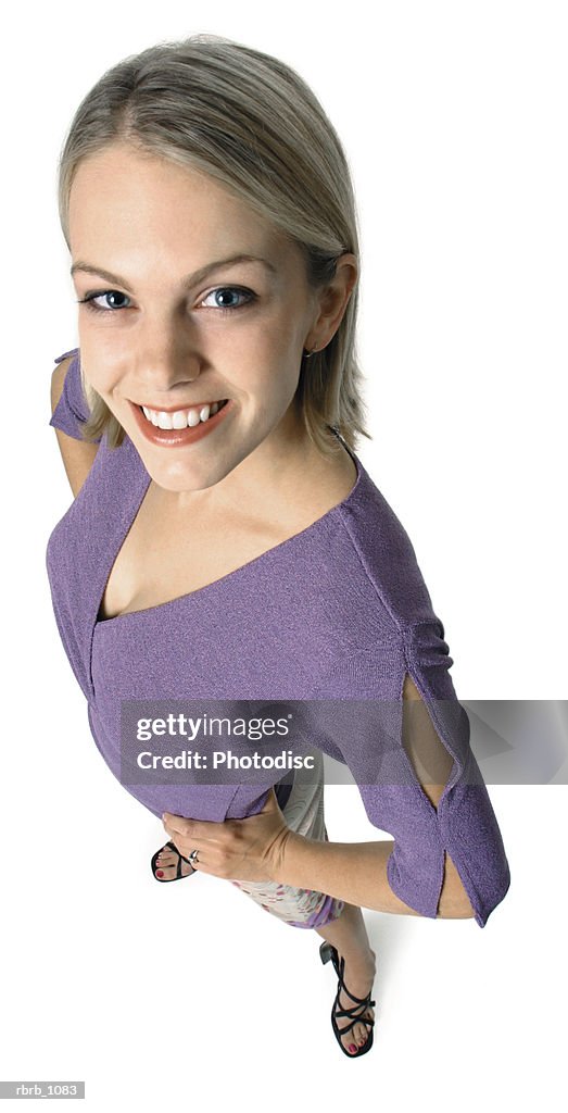 An attractive young caucasian blonde woman in a purple blouse smiles up at the camera