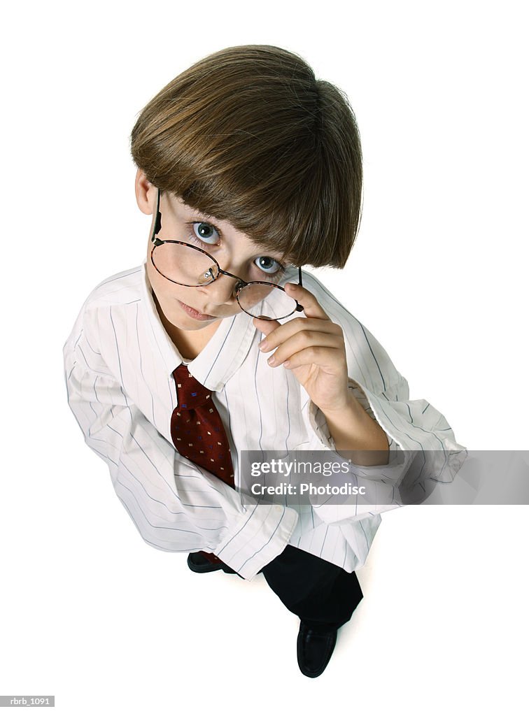 A caucasian male child dresses up in a shirt and tie and glasses and glares up at the camera