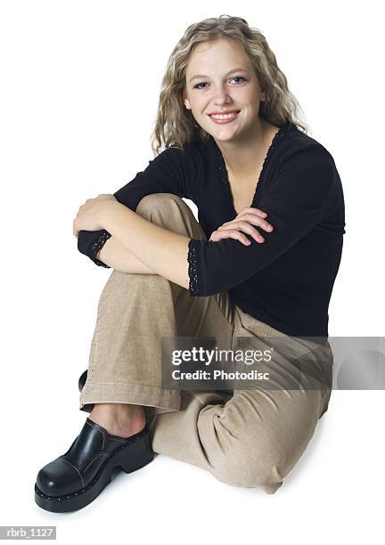 a teenage caucasian blonde female in tan pants and a black shirt sits down and smiles - pants down bildbanksfoton och bilder