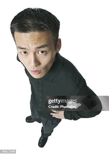 an asian man dressed in black looks annoyed as he glances up at the camera - arms akimbo stock pictures, royalty-free photos & images