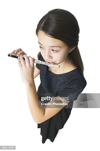 high angle shot of an asian female teen in a black dress as she plays her flute - bläser stock-fotos und bilder