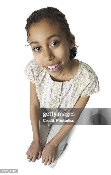 an african american female child in tan pants and a floral print shirt kneels down as she smiles up at the camera - pants down bildbanksfoton och bilder