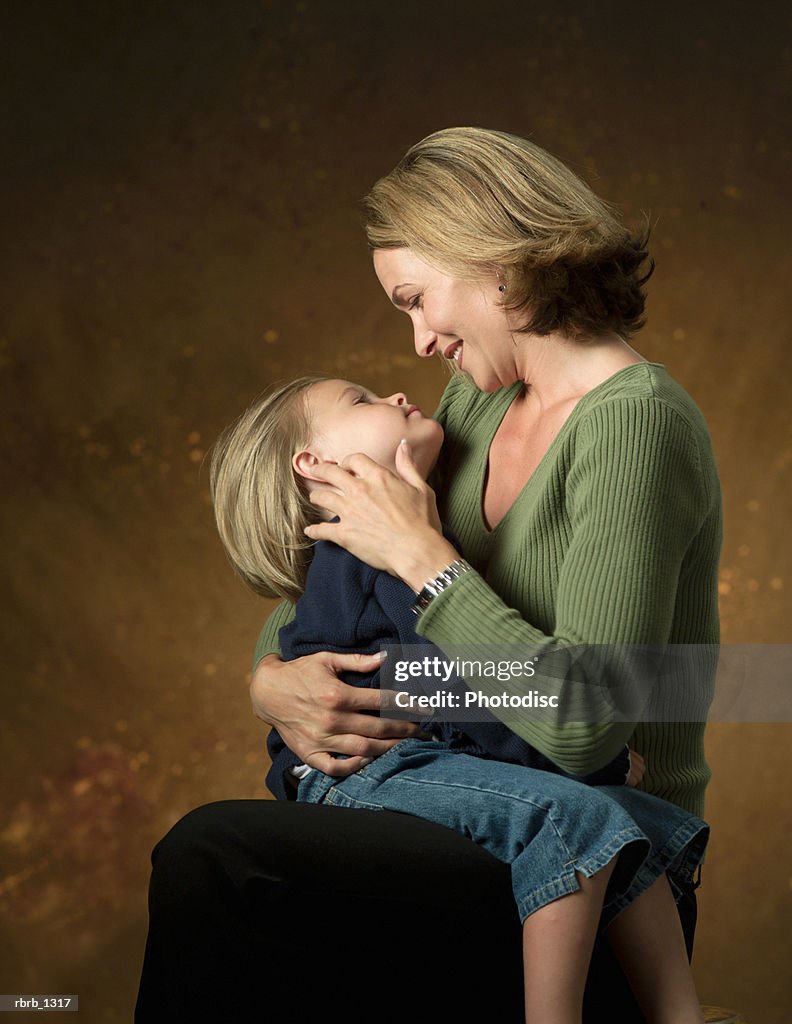 A blonde caucasian mother looks lovingly at her young daughter as she sits on her lap