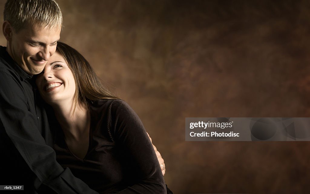 Studio portrait of a young caucasian couple as they hold each other and laugh together