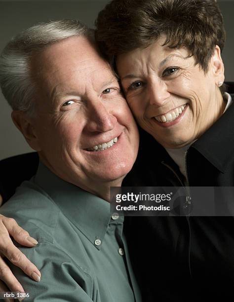 studio portrait of an elderly caucasian couple as they embrace and smile at the camera - smile bildbanksfoton och bilder