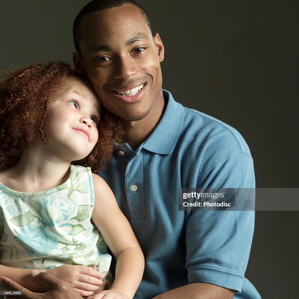 Studio portrait of an african american father smiling while holding his young daughter