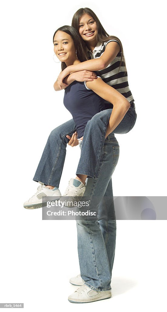 Two ethnic teenage sisters play as one carries the other on her back