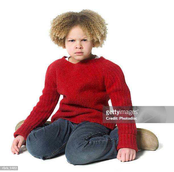 a caucasian female child with curly hair in a red sweater kneels down and scowls - curly stock pictures, royalty-free photos & images