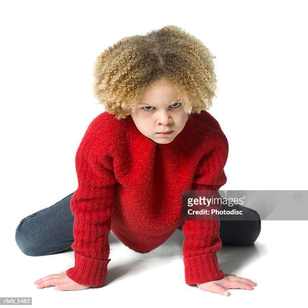a caucasian female child with curly hair in a red sweater crouches down and scowls - curly stock pictures, royalty-free photos & images