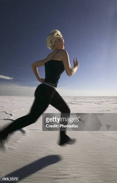 a young caucasian blonde woman jogs across a barren landscape - across stock pictures, royalty-free photos & images