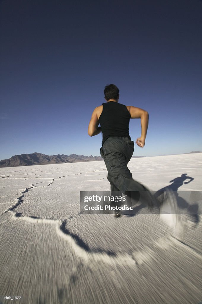 A young hispanic man jogs through the vast open desert