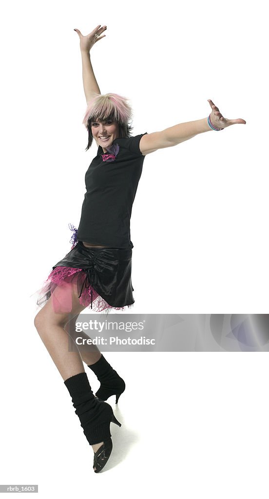 A young caucasian woman in a retro punk outfit strikes a fun dance pose