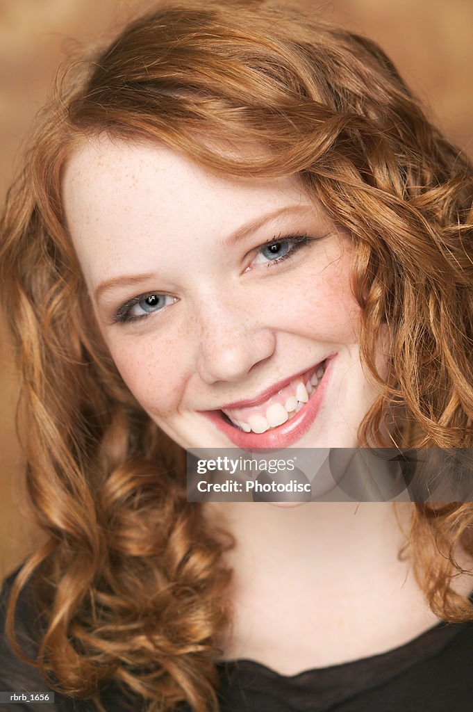 Portrait of an attractive female redheaded teen in a black shirt as she smiles brighty