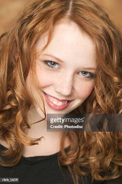 portrait of a female redheaded teen in a black shirt as she flashes a cute smile - smile stock-fotos und bilder