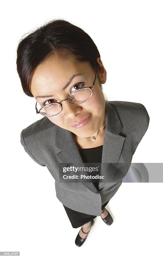 An adult asian business woman in a grey suit and glasses smiles up at the camera