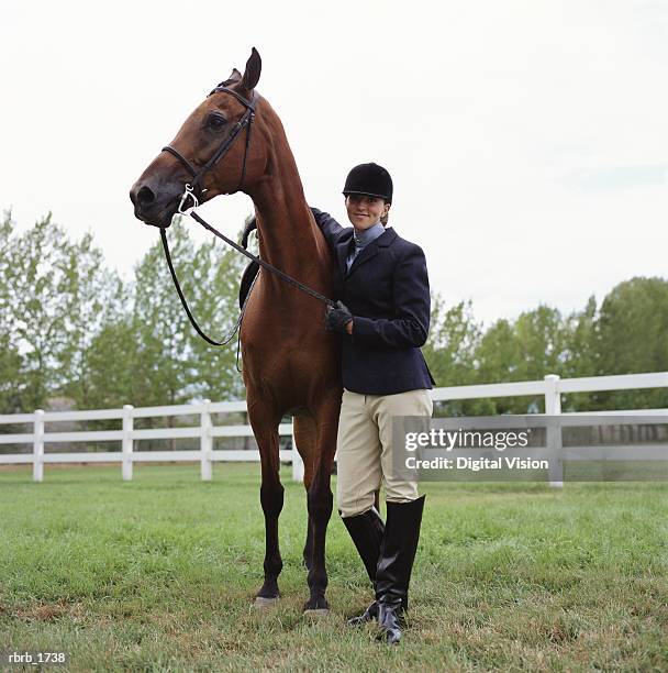 a caucasian female horseback rider stands with her horse and smiles - body modification stock-fotos und bilder