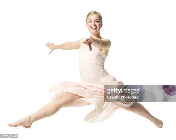 a caucasian blonde female teen in a pink ballet outfit jumps out in a dance routine - ot ストックフォトと画像