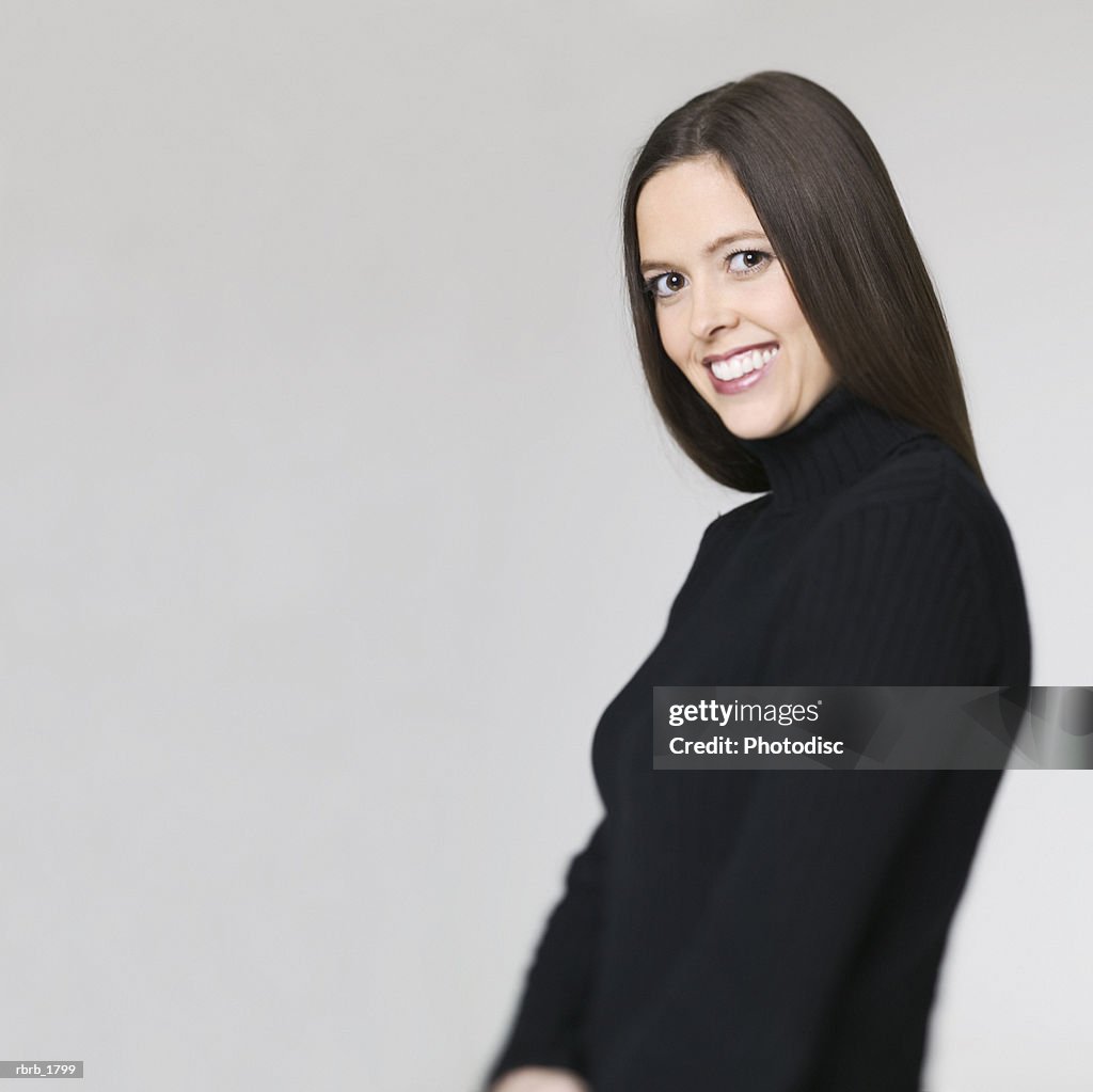 Medium shot of a young adult woman in a black sweater as she turns and smiles