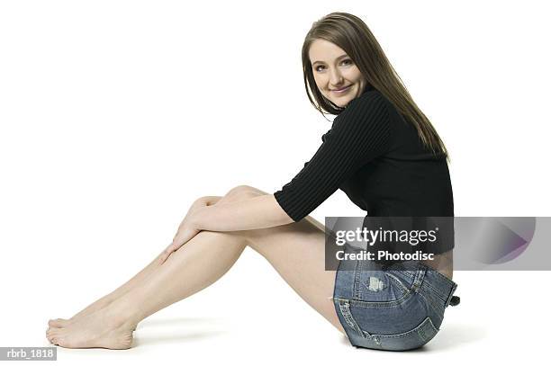 full body shot of a teenage brunette female in a black sweater as she sits and smiles - ot ストックフォトと画像
