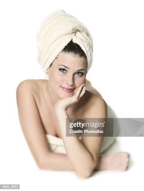 full body shot of a young adult woman with her hair wrapped in a towel as she lays down and smiles - cooling down stock-fotos und bilder