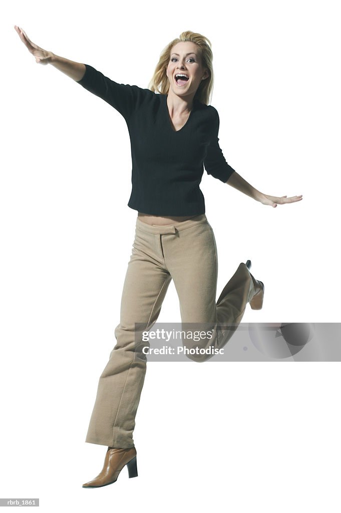 Full body shot of a young adult blonde female in a black sweater as she playfully jumps through the air