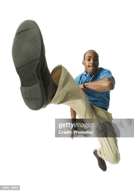 full body shot of a young adult male in a blue shirt as he jumps and kicks through the air - man full body isolated stock pictures, royalty-free photos & images