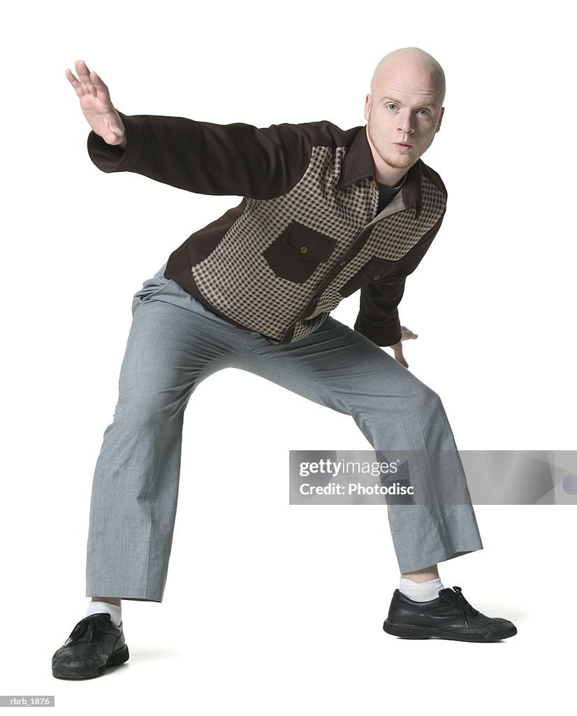 Full body shot of a young adult male in a brown checkered shirt as he strikes a silly pose