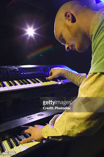 medium shot of a young adult male as he wildly plays his keyboards up on stage - moderne rock stockfoto's en -beelden