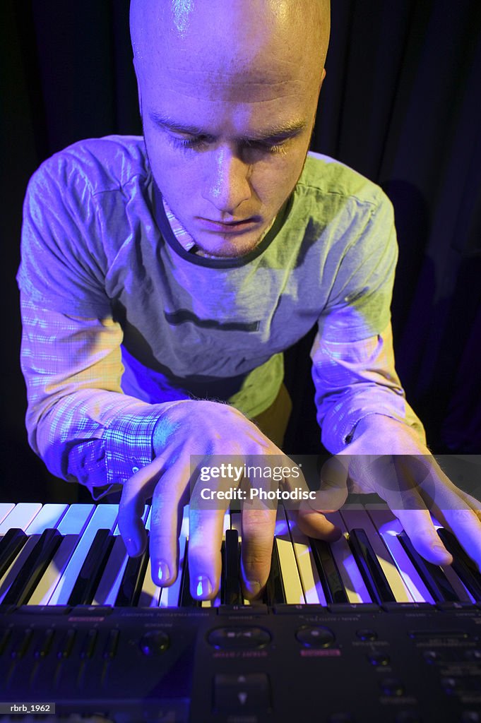 Medium shot of a young adult male as he wildly plays his keyboard while up on stage