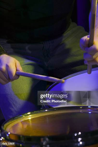 close up on a set of hands holding drum sticks as they play the drums - rock moderne photos et images de collection