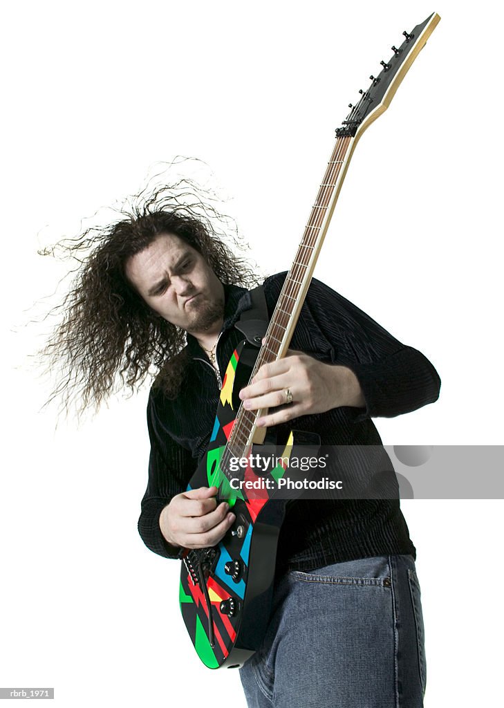 Medium shot of a young adult male as he plays his electric guitar