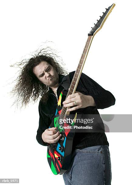 medium shot of a young adult male as he plays his electric guitar - moderne rockmusik stock-fotos und bilder