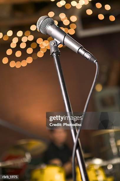 close up shot of a microphone in front of a rock band - moderne rock stockfoto's en -beelden