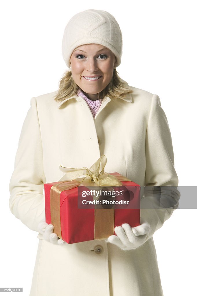 Medium shot of a young adult female in a winter hat and coat as she holds a present