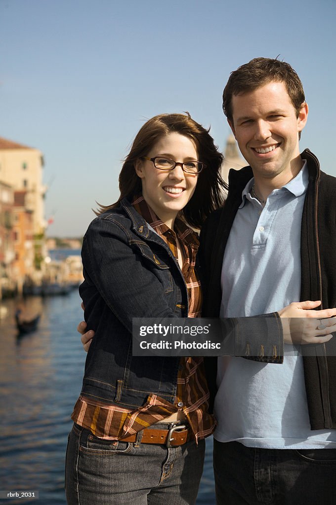 Medium shot of a young adult couple as they pose near the grand canal in venice italy