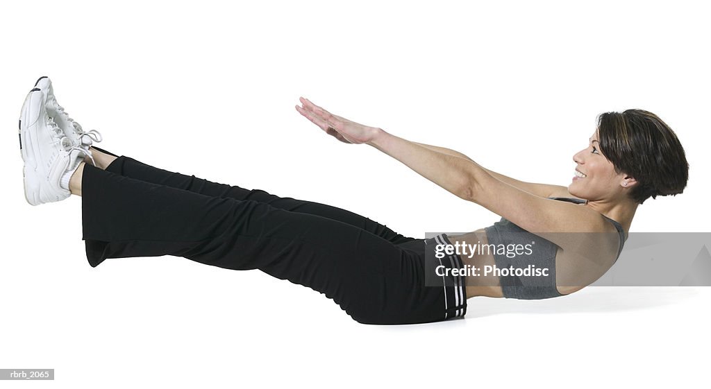 Full body shot of an adult woman in a workout outfit as she lays down and stretches out