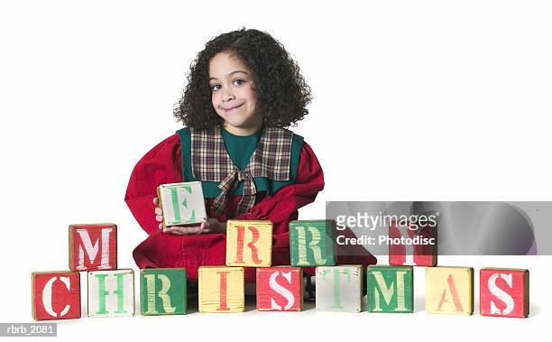 full body shot of a young female child as she sits next to blocks that say merry christmas - next imagens e fotografias de stock