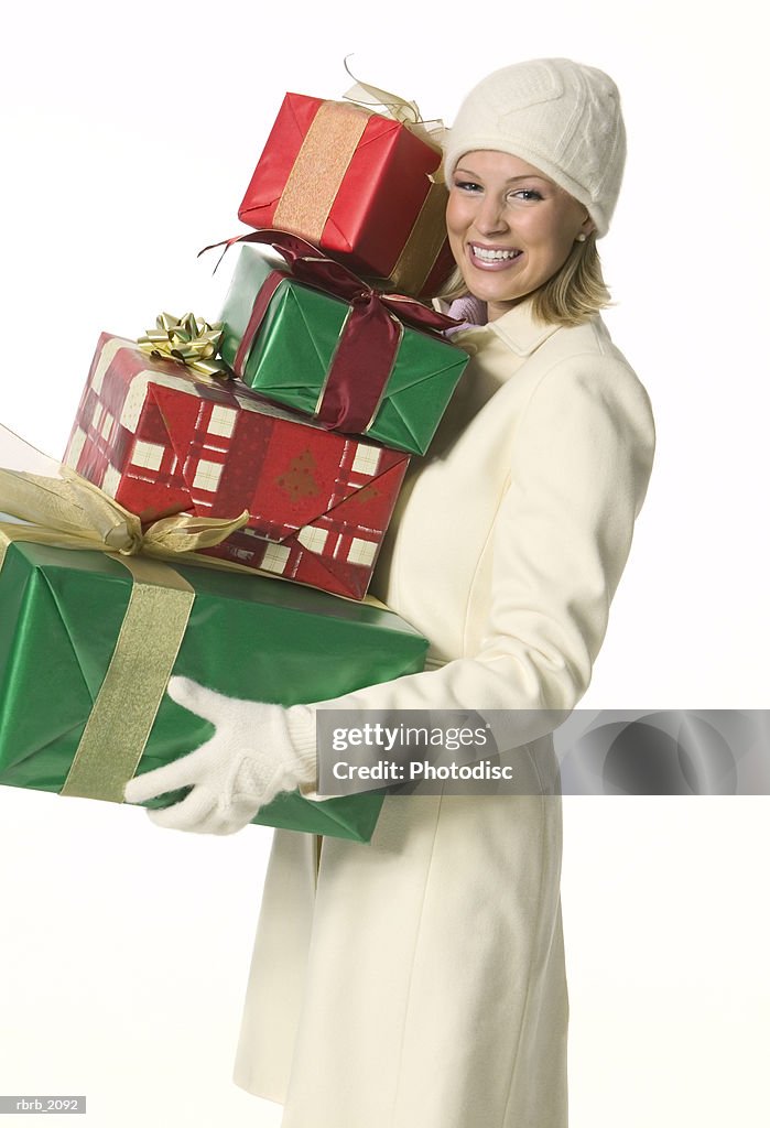 Medium shot of a young adult woman in a winter outfit as she holds a stack of presents