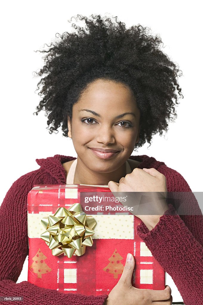 Medium shot of a young adult woman as she wraps her arms around a christmas gift