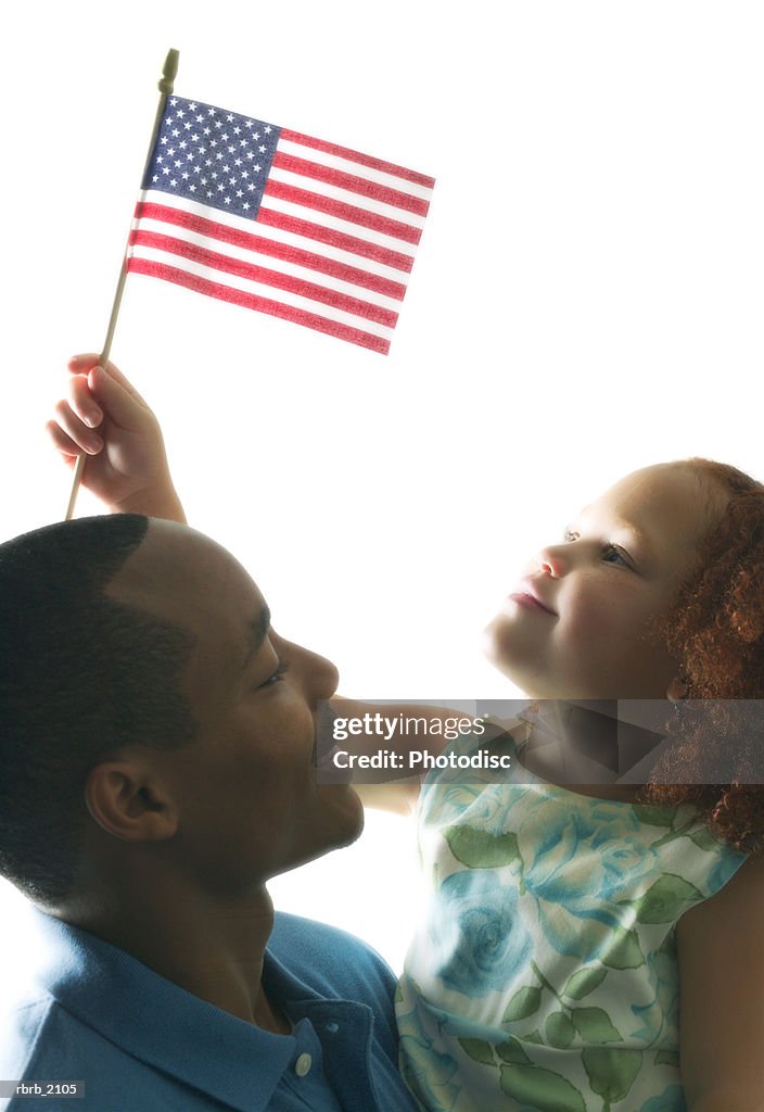 Medium shot of a father and daughter as the girl waves an american flag