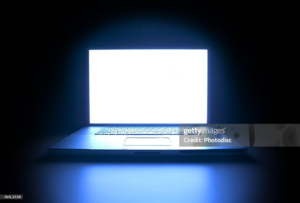Shot of a laptop computer as the screen glows in the darkness