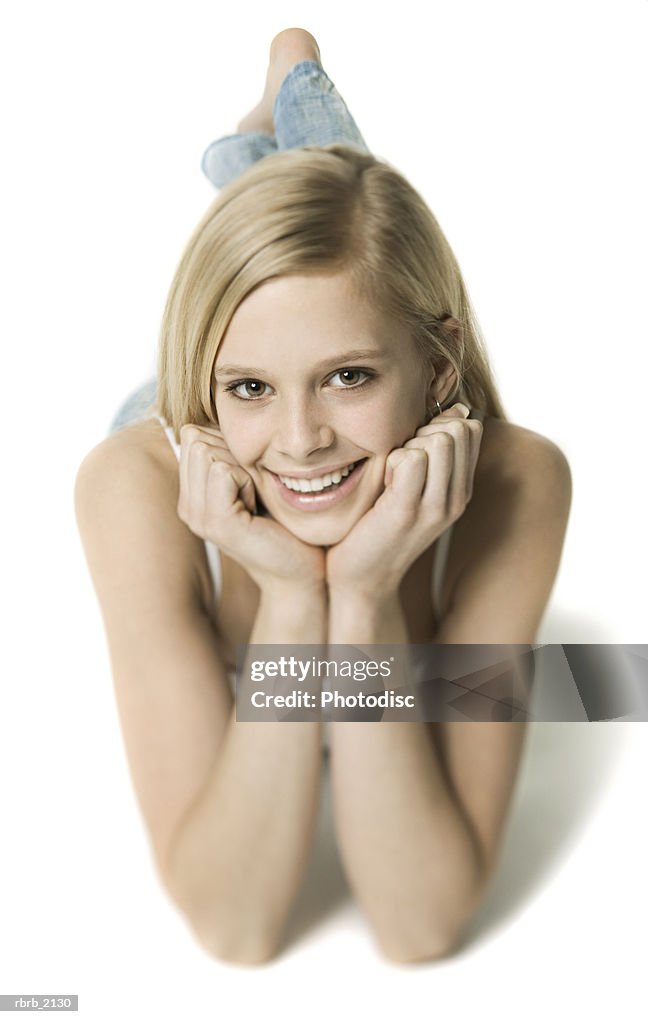 Full body shot of a blonde teenage female as she lays down and smiles at the camera